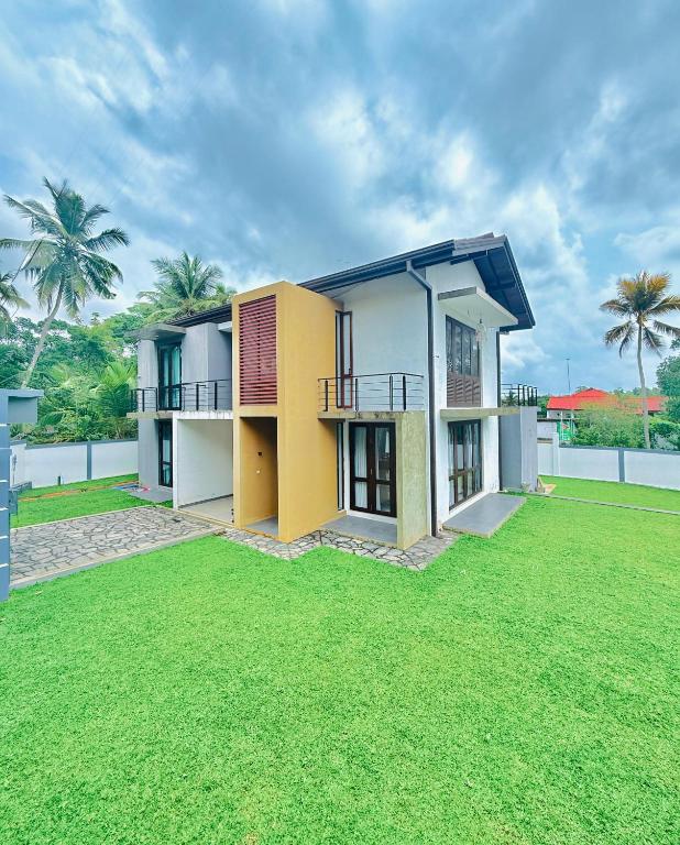 a house with a green lawn in front of it at Alex's Place in Ja-Ela