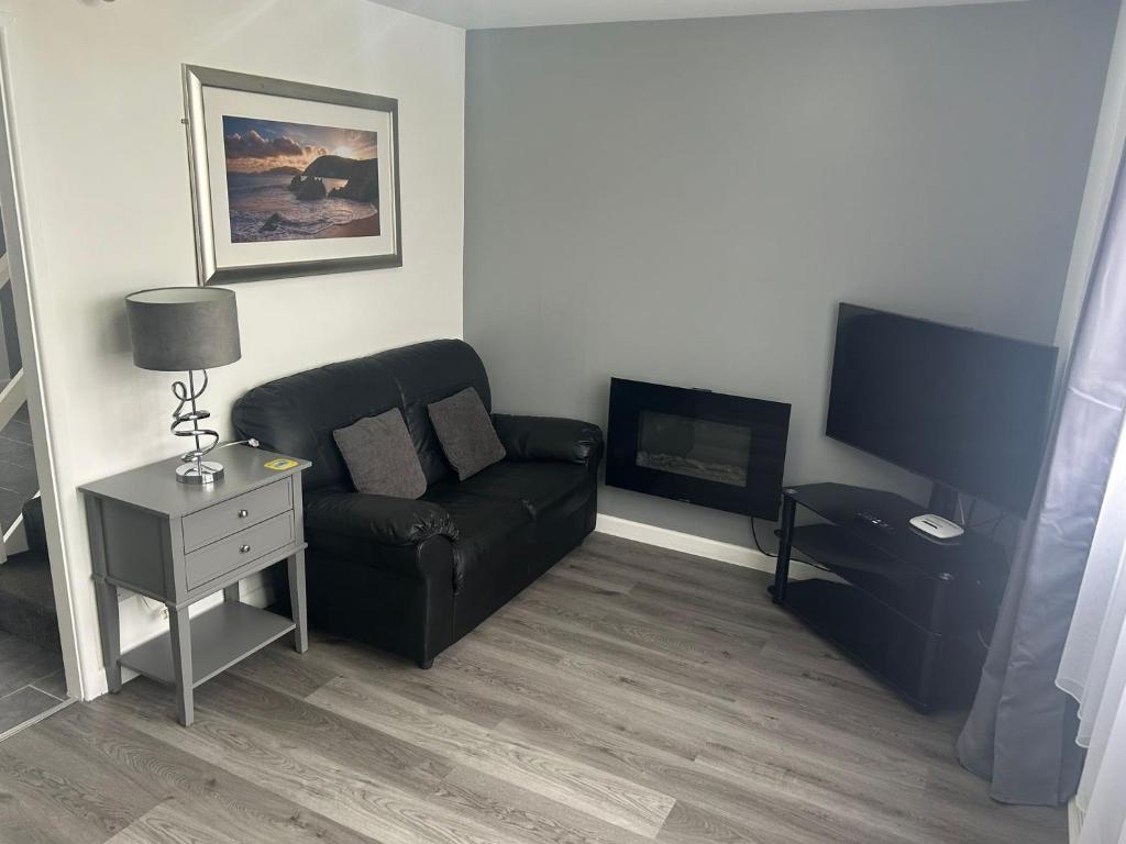a living room with a black couch and a tv at Charming 2 Storey Holiday Villa in Dawlish Warren in Dawlish Warren