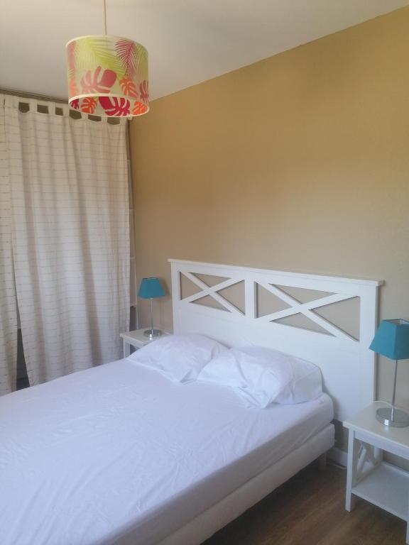 a bedroom with a white bed and two night stands at Le petit paradis in Soustons