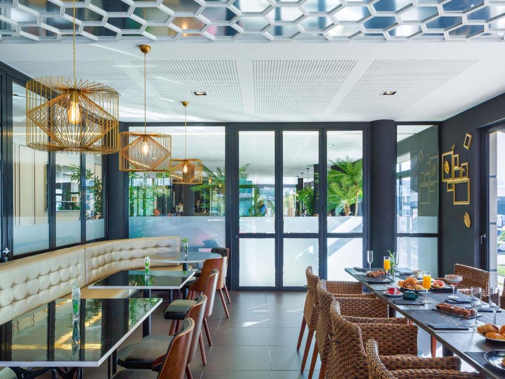 um restaurante com mesas longas, cadeiras e janelas em Ibis Styles A Coruna na Corunha