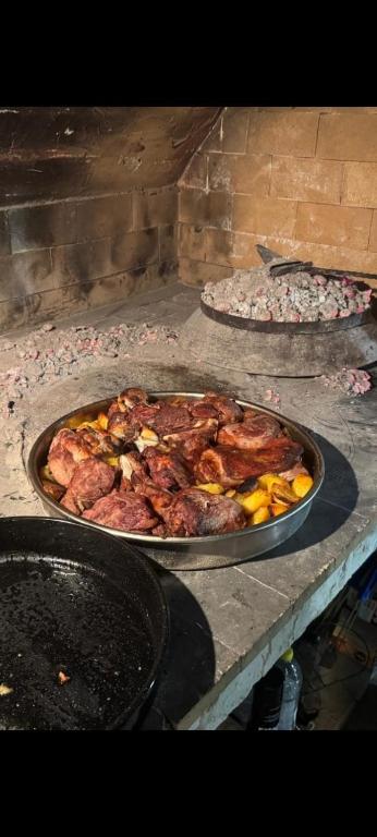 a table with a pan of meat and other food at Apartman Nika in Drniš