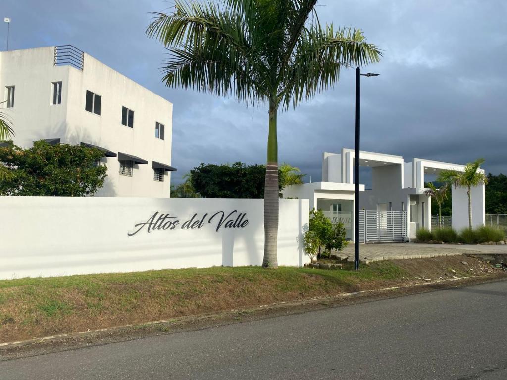 un bâtiment blanc avec un palmier devant dans l'établissement Peaceful Cottage, à Santiago de los Caballeros