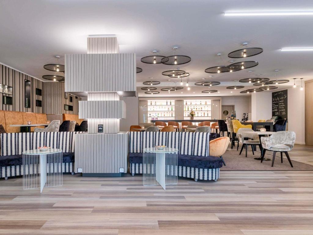 un restaurant avec des tables et des chaises bleues et blanches dans l'établissement Mercure Hannover Oldenburger Allee, à Hanovre