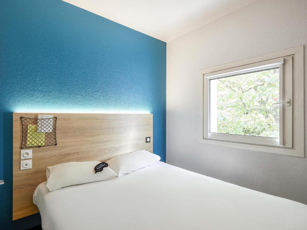 Un dormitorio con una cama blanca y una ventana. en hotelF1 Lyon Saint Priest, en Saint-Priest