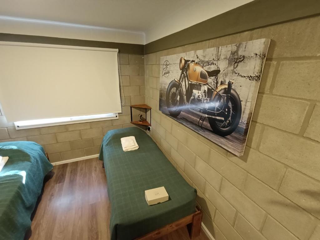 una habitación con una cama y una foto de una motocicleta en la pared en Cyclotel Motoposada, en Valle Hermoso