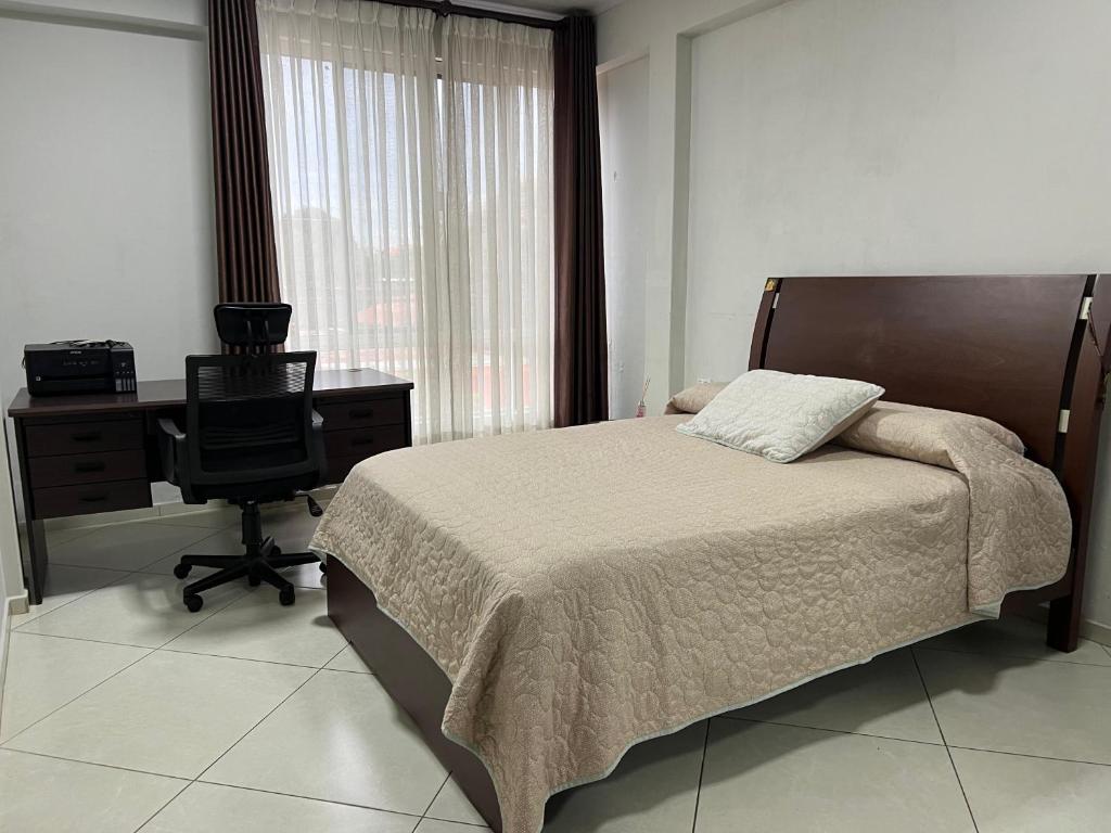 ein Schlafzimmer mit einem Bett, einem Schreibtisch und einem Stuhl in der Unterkunft Casa linda y cómoda en SC in Santa Cruz de la Sierra
