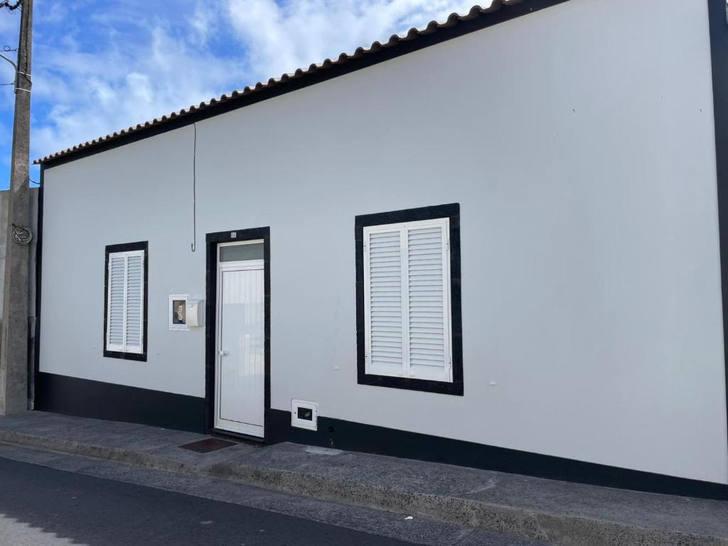 a white building with two windows and a door at Casa Dona Rosa in Ponta Delgada