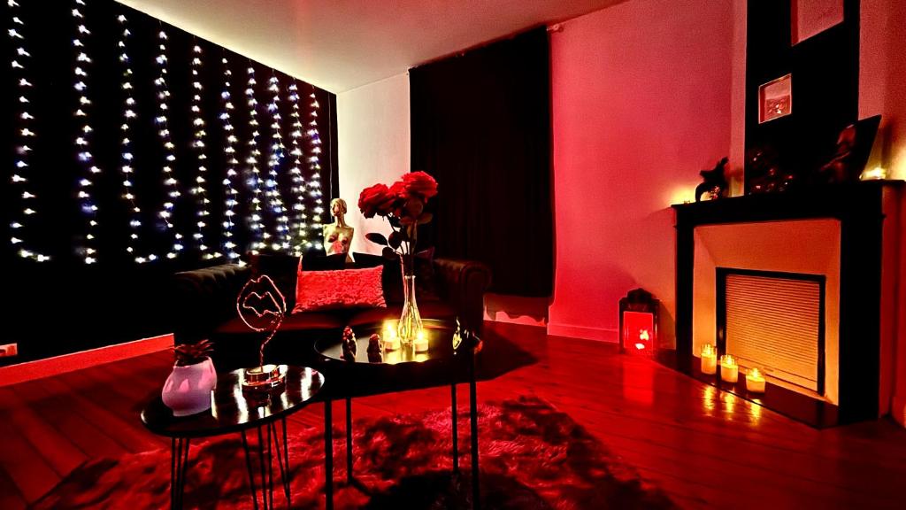 a living room with a fireplace and a red wall with lights at Love room 10 minutes de Nantes in Thouaré-sur-Loire
