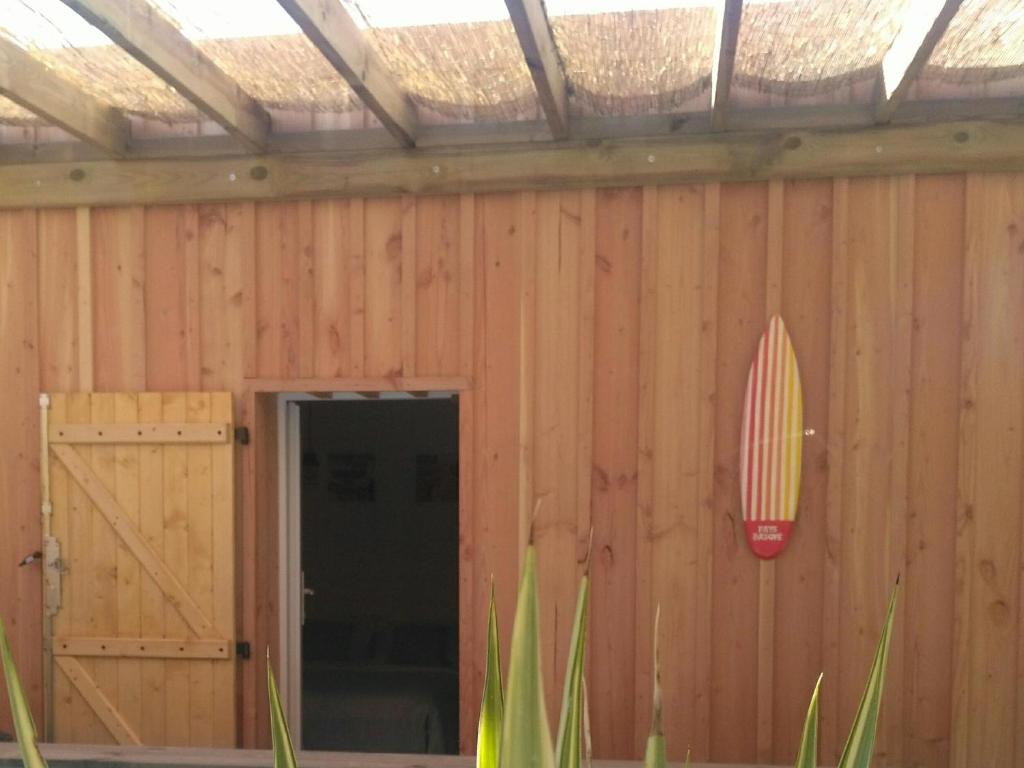 a surfboard on the wall of a wooden building at La Cabane Bordeaux St Augustin in Mérignac