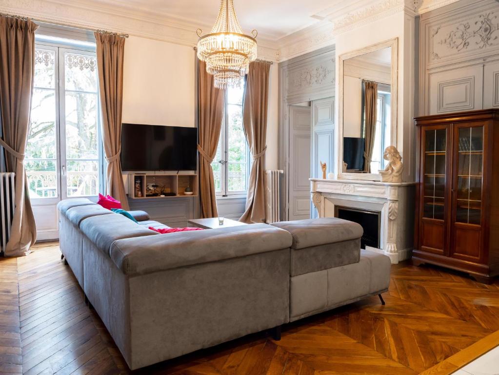 a living room with a couch and a television at Appartement 100m2 d'élégance au sein d'un Château caché à 10min de Lyon in Villeurbanne