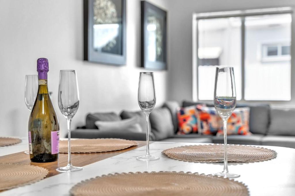 a table with a bottle of wine and four glasses at Costerra Miami 2BR in Miami