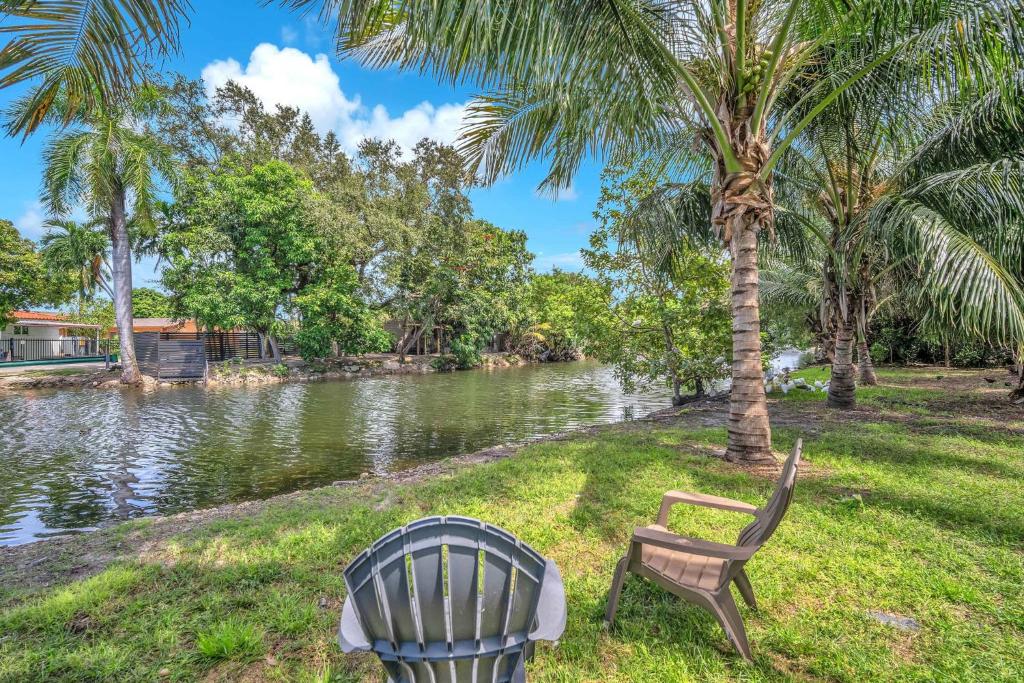 a chair sitting next to a palm tree next to a river at Costerra Miami 2BR Near Airport in Miami