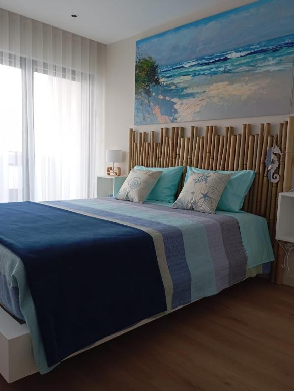 a bedroom with a large bed with a blue blanket at Mirante Monte e Mar in Esposende