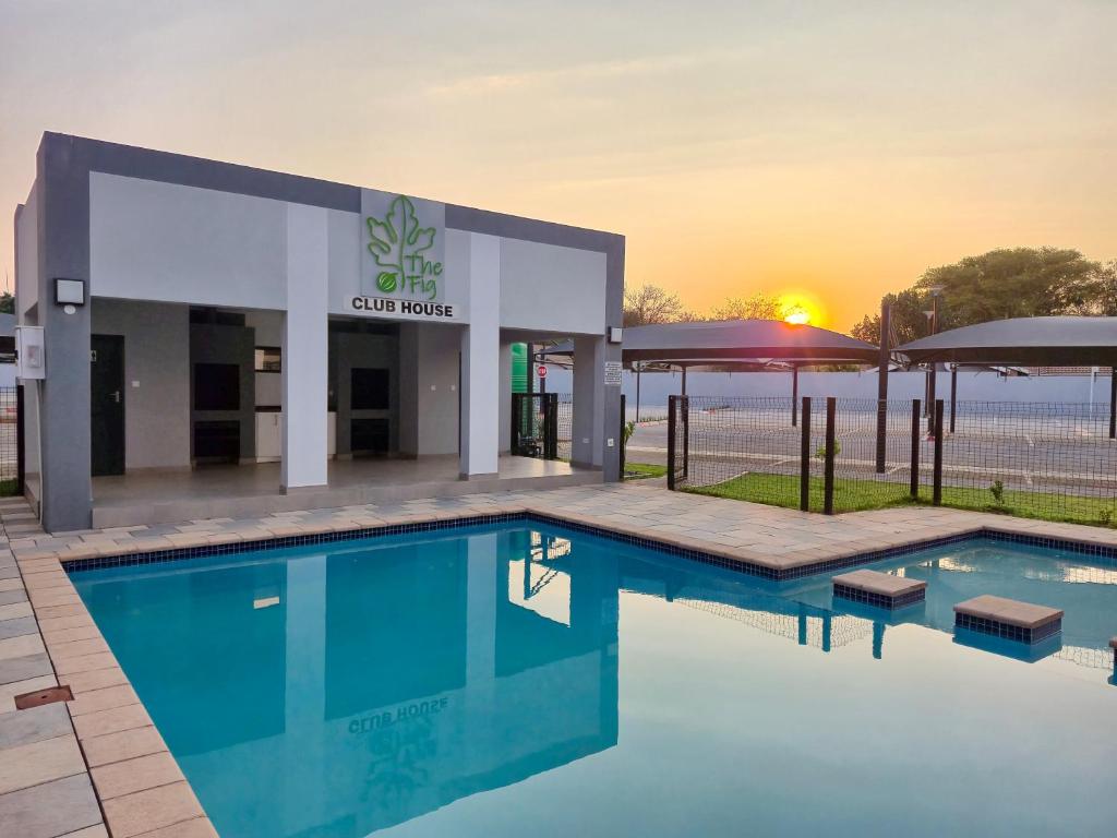 ハボローネにあるZenith Retreatの夕日が沈む建物の前のプール