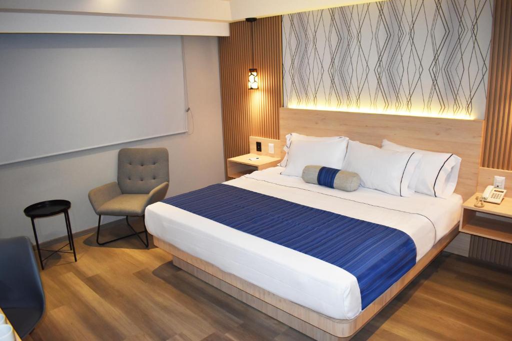 メキシコシティにあるHotel Torremolinos Vallejo Ciudad de Mexicoの大きなベッドと椅子のあるホテルの部屋