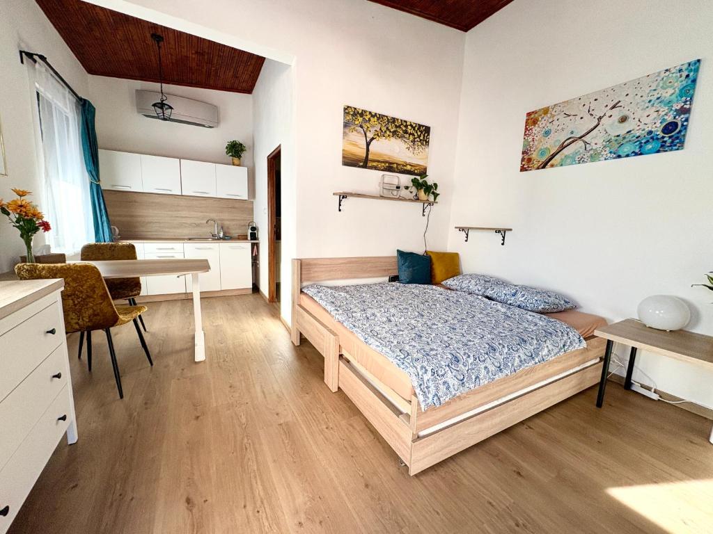 a bedroom with a bed and a table and a kitchen at Little park house with car charger in Stupava