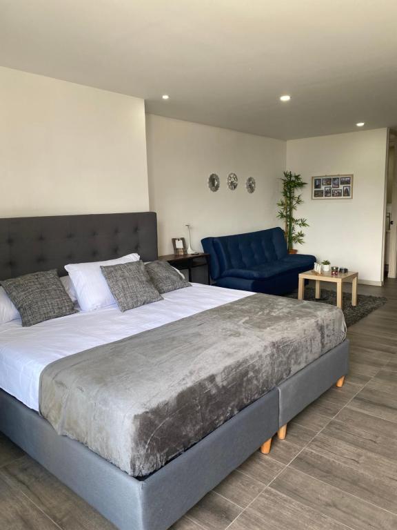 a bedroom with a large bed and a blue chair at Class 48 Exclusivo y elegante apartamento in Sabaneta