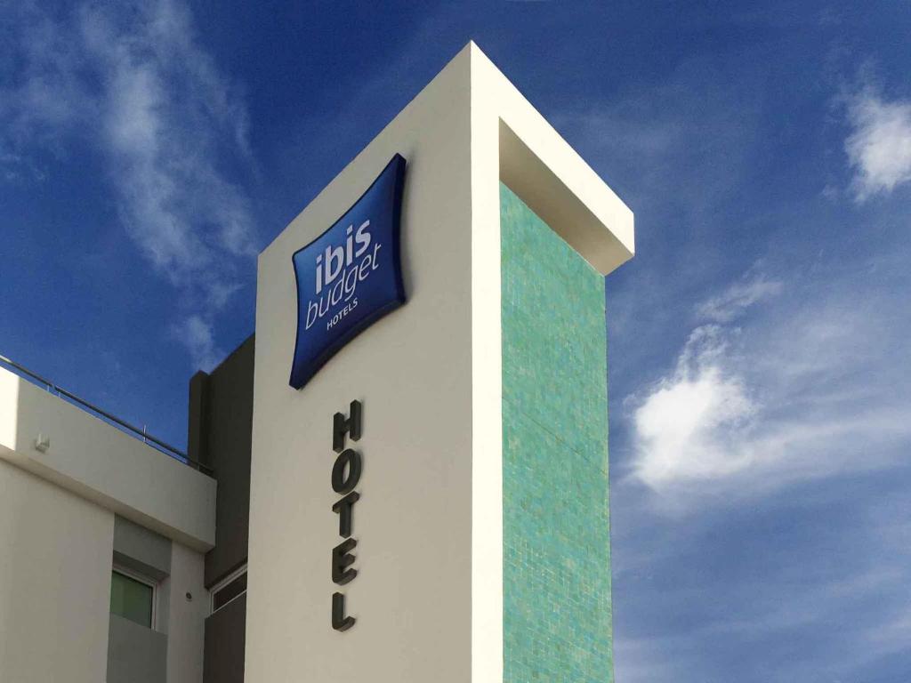 Un edificio blanco con un cartel azul. en ibis budget Vitry sur Seine N7, en Vitry-sur-Seine