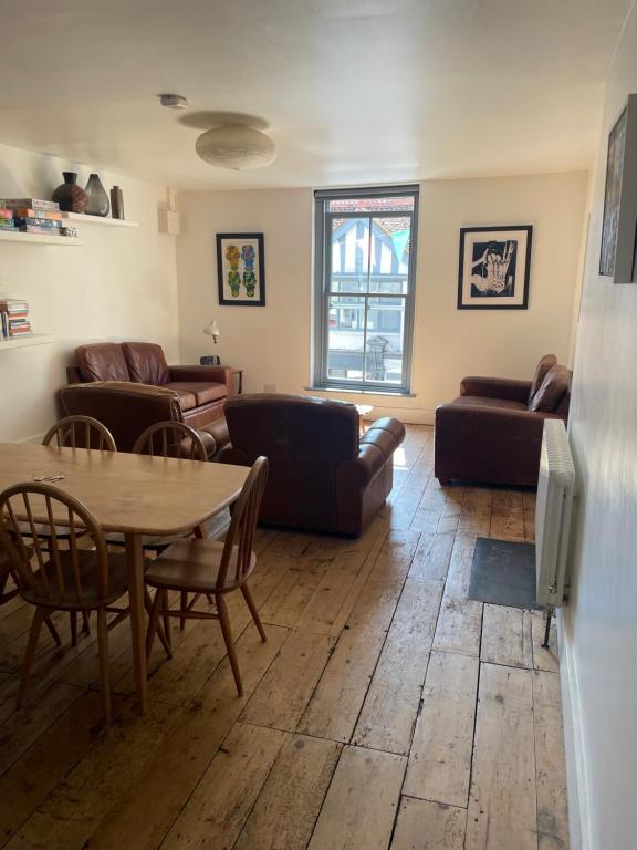 a living room with couches and a table and chairs at Bright spacious flat in the heart of town in Falmouth