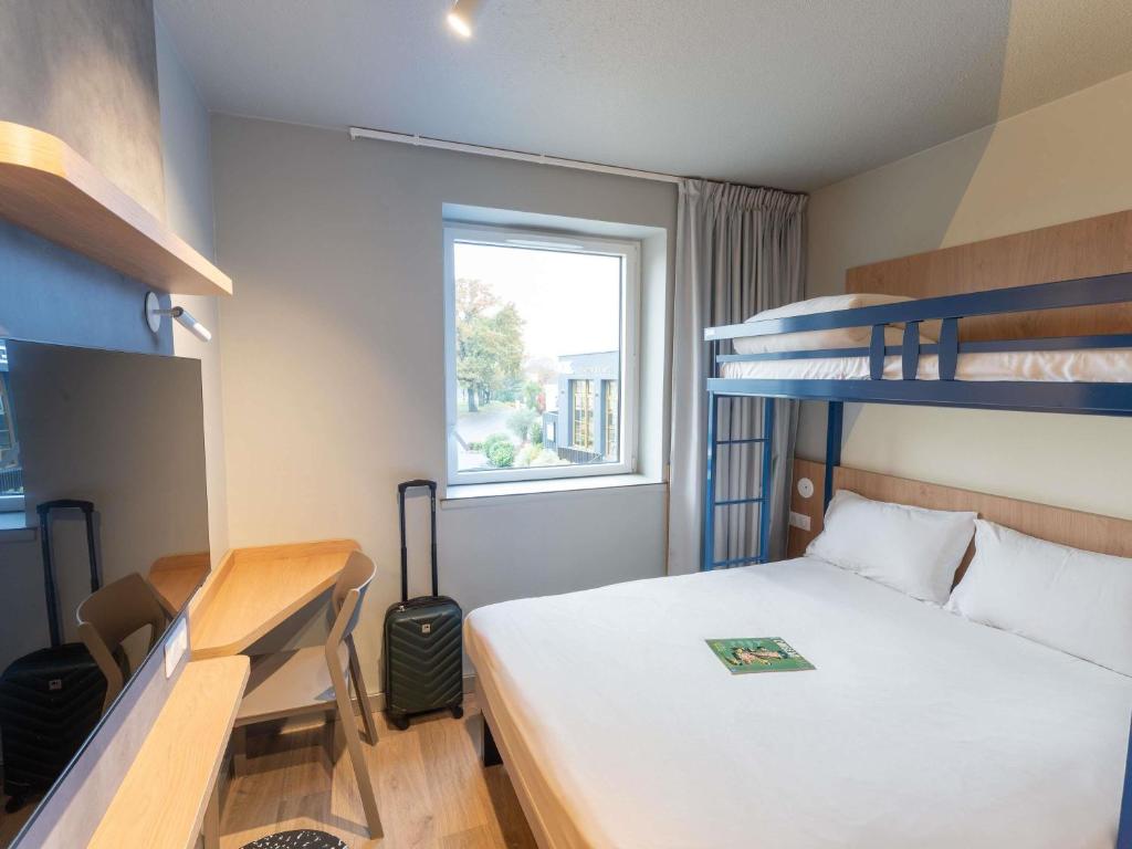 a bedroom with a bed and two bunk beds at Hotel Ibis Budget Rennes Cesson in Cesson-Sévigné