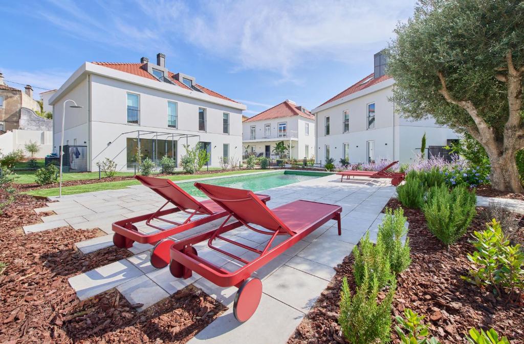 Un patio con dos tumbonas rojas y una piscina. en Luxury Villa by the Sea w Salty Pool, by TimeCooler, en Oeiras