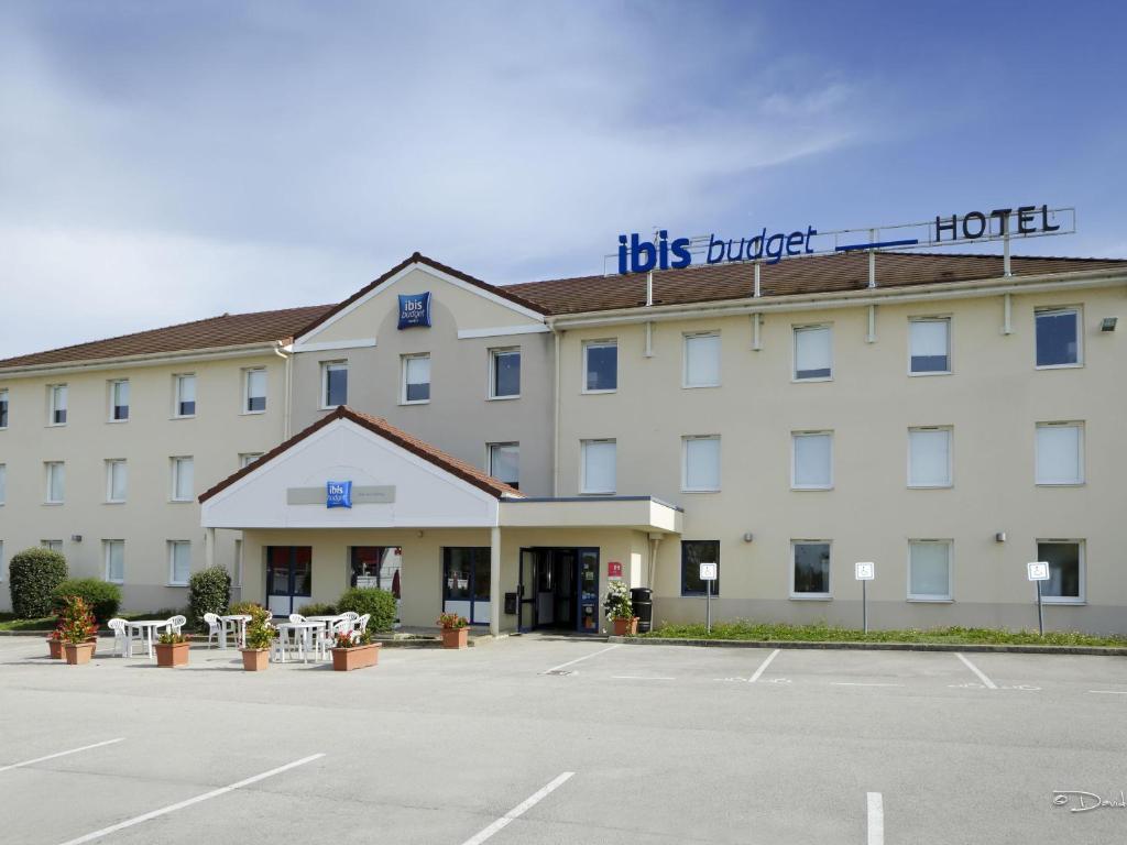 Un hotel con un estacionamiento enfrente. en Ibis Budget Dole-Choisey, en Dole