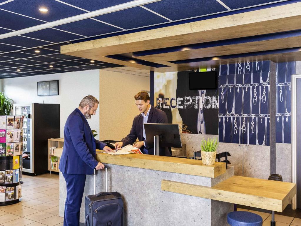Dos hombres de pie en un mostrador de una tienda en ibis budget Paris Porte d&#39;Italie Est, en Le Kremlin-Bicêtre