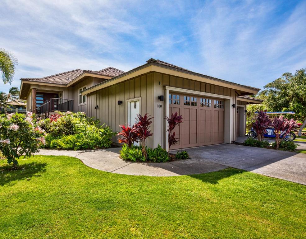 a house with a garage and a grass yard at HAWAIIAN JEWEL Family friendly KaMilo 4BR Home Walk to Pauoa Beach in Waikoloa