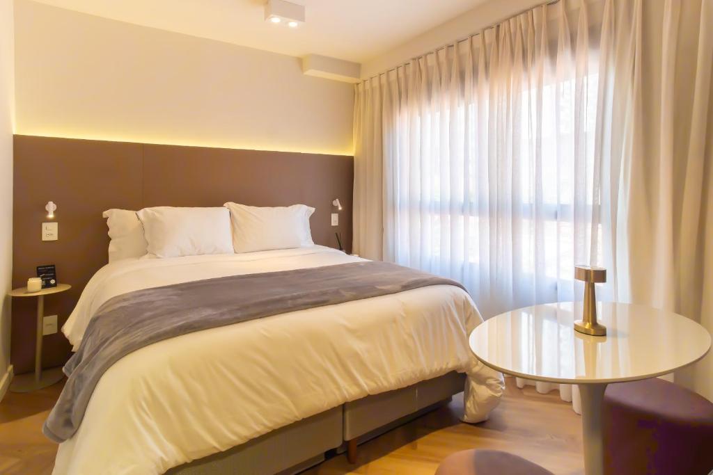 a bedroom with a large bed and a table at Luxury Studio for 4 People - Allianz Park in Sao Paulo