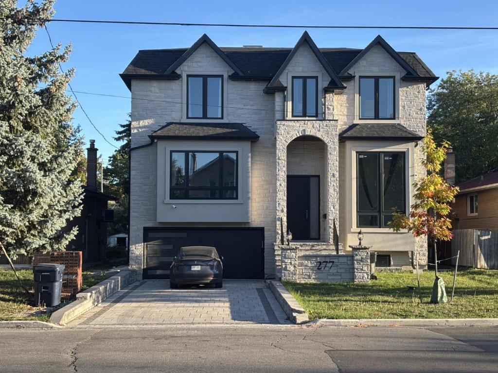 a house with a car parked in the driveway at Cozy Suite in Brand New Luxury Home in Toronto