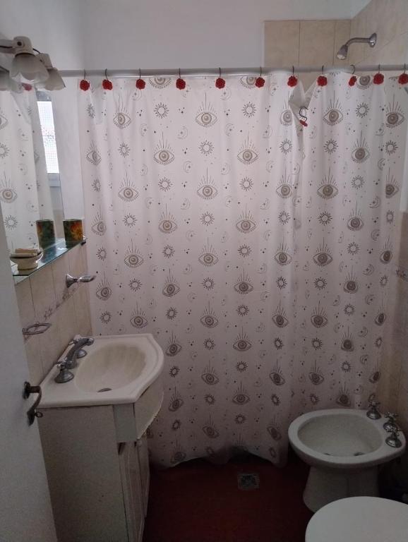 a bathroom with a sink and a toilet and a shower curtain at Ribera Apart in Necochea