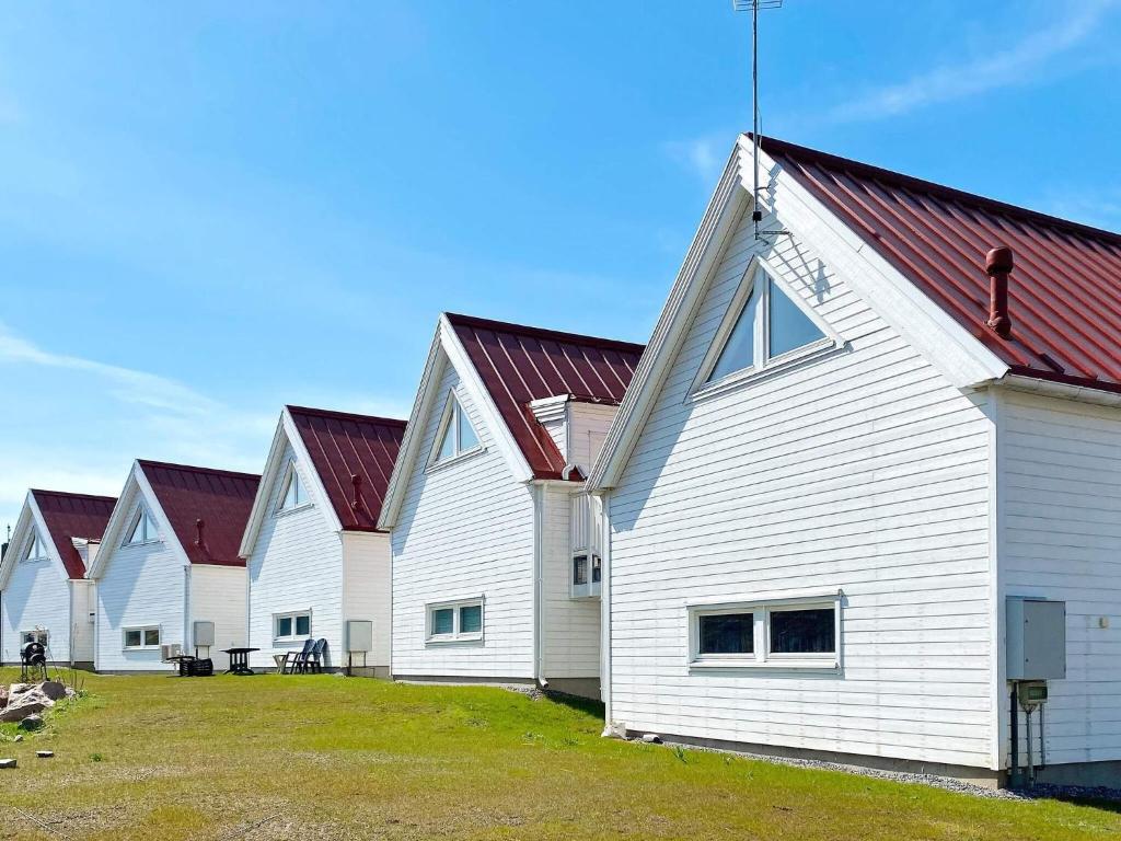 a row of white barns with red roofs at 4 star holiday home in Åkersberga in Åkersberga