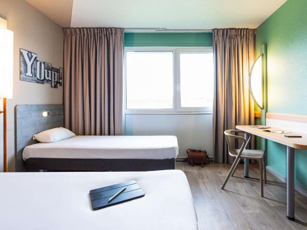 Una habitación de hotel con dos camas y un escritorio. en ibis budget Angoulême Nord, en Champniers