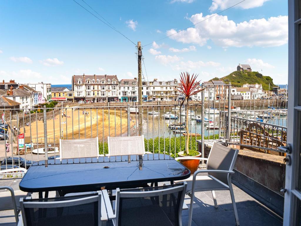 ein Tisch und Stühle auf einem Balkon mit Blick auf einen Hafen in der Unterkunft Manor Cottage in Ilfracombe