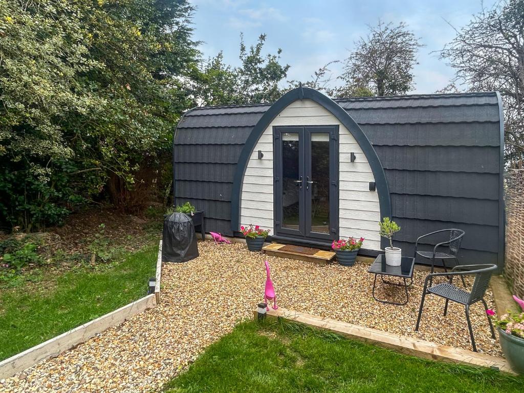 a small black and white shed with a table and chairs at Thula Lodge in Chichester