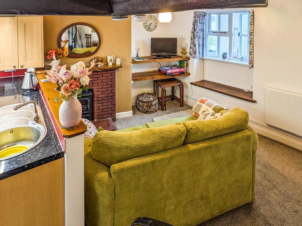 a living room with a yellow couch and a kitchen at Wee Cottage in Paignton