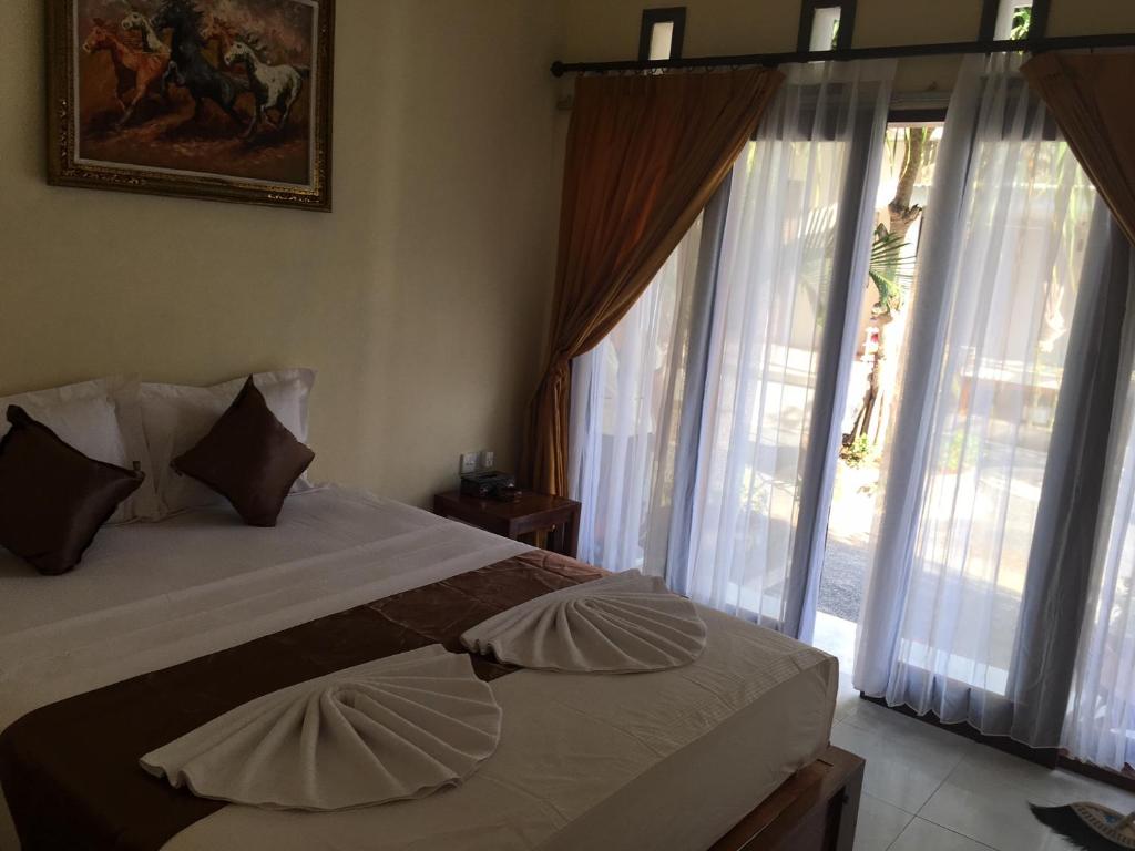 a bedroom with a bed with pillows and windows at BBS Homestay in Nusa Lembongan