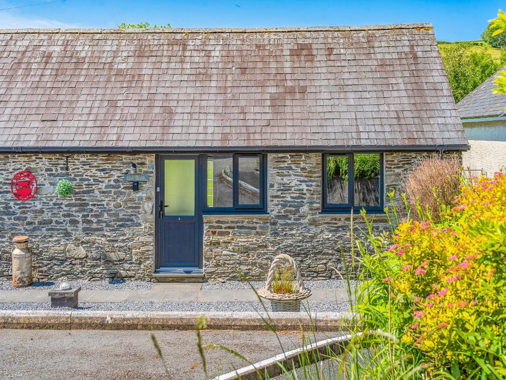 ein Steinhaus mit einer blauen Tür und Fenstern in der Unterkunft The Old Cowsheds 5 - Llanilar - Uk49790 in Cribyn