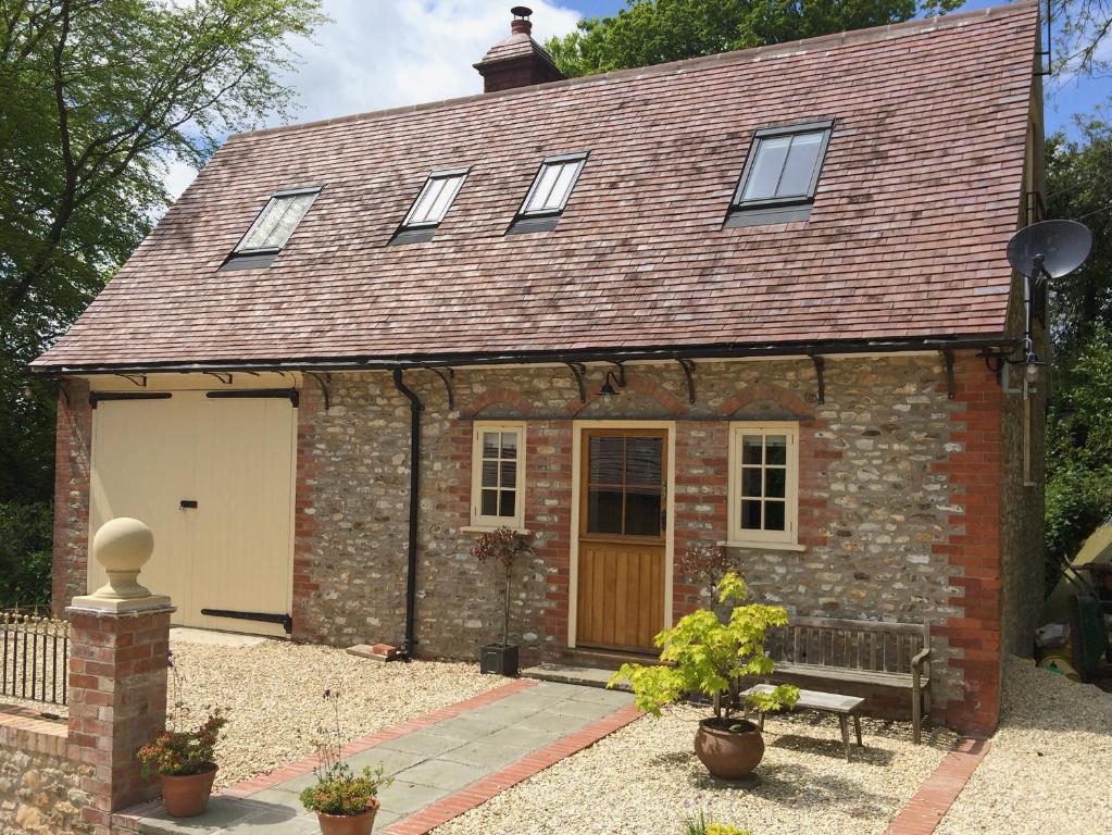 a small brick house with a bench in front of it at The Coach House The Old Rectory in Buckland St Mary