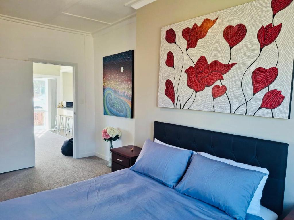 a bedroom with a blue bed and a painting on the wall at The cottage coghill in Whitianga