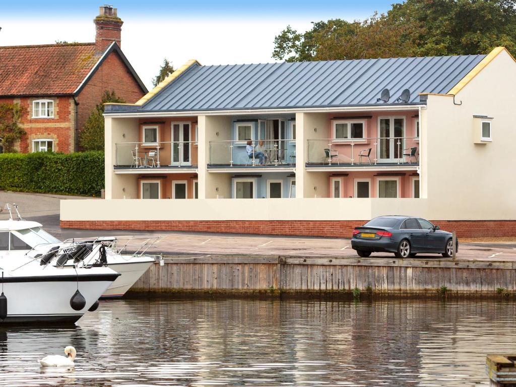 a car parked on a dock next to a house at Crested Grebe - Ukc2109 in Wroxham