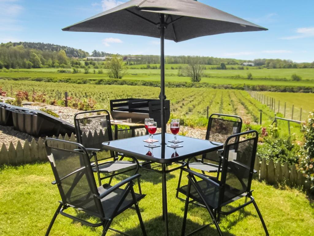 un tavolo con bicchieri da vino e un ombrello di Kilfillan Cottage a Garlieston