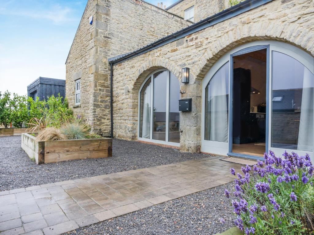 a brick building with large windows and purple flowers at The Coach House in Whittonstall