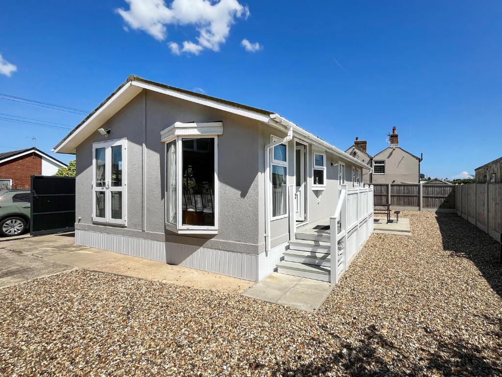 ein kleines graues Haus auf einer Kiesauffahrt in der Unterkunft The Lodge in Chapel Saint Leonards