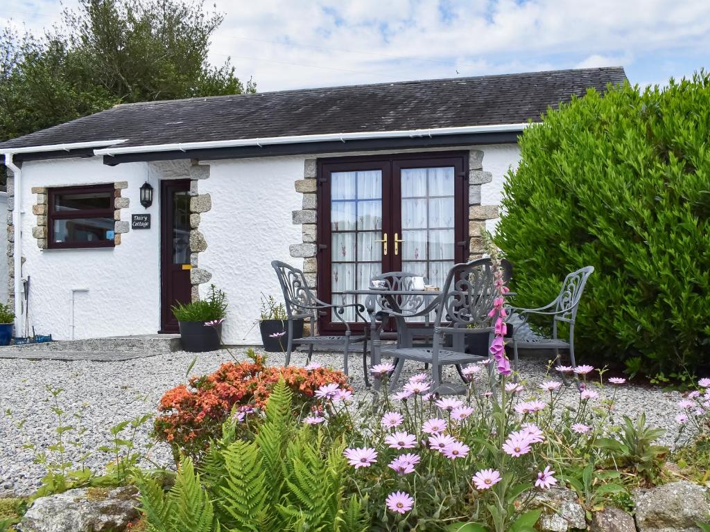 a cottage with a table and chairs in a garden at Dairy Cottage - Uk49834 in Lanivet