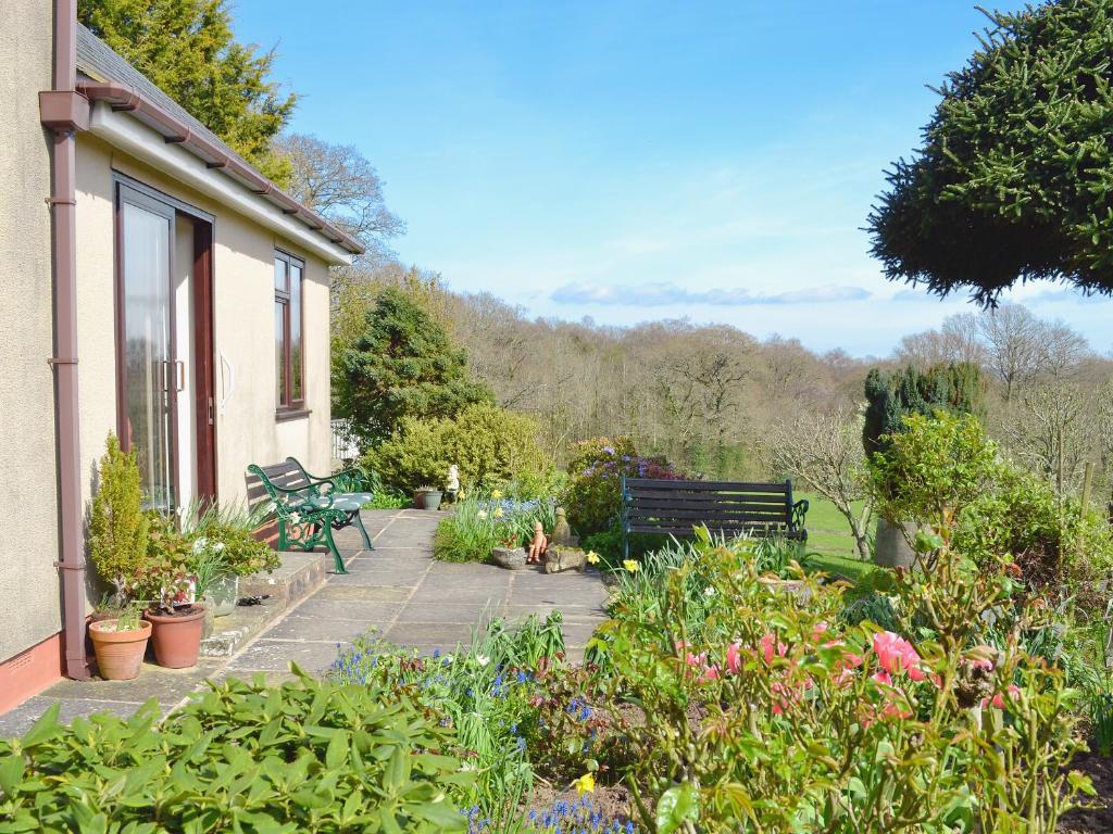 een tuin met een bank en wat planten en bloemen bij Rose Cottage in Cheriton Bishop