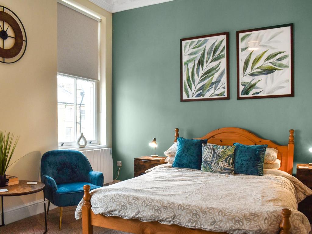a bedroom with a bed and a blue chair at Denelea Studio 1 - Uk49952 in Scarborough