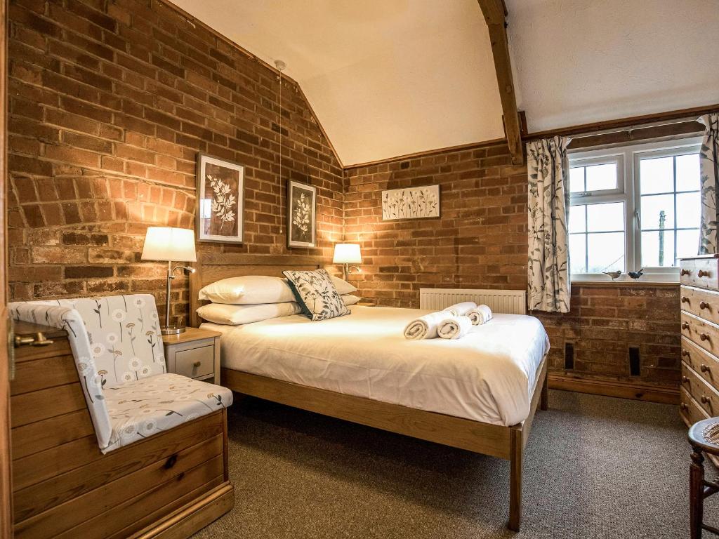 a bedroom with a bed and a brick wall at Yarlington Mill in Ledbury