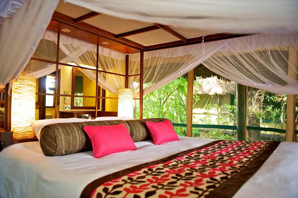 ein Schlafzimmer mit einem großen Bett mit roten Kissen in der Unterkunft Samburu Intrepids Tented Camp in Archers Post