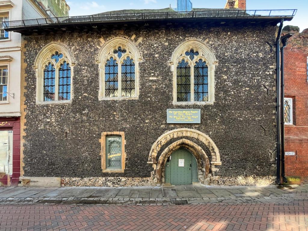 an old brick building with a green door at The Yeomans Cottage, Eastbridge Hospital in Canterbury
